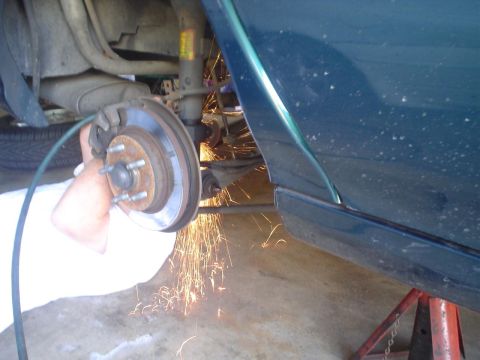 1993 Ford Taurus - Sparks fly as a mechanic works on the rear brake assembly of a vehicle.