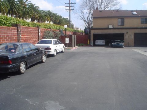 1993 Ford Taurus - Two sedans are parked outside a garage, where a dark coupe is visible inside.