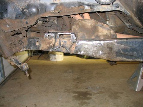 1986 Ford F-150 - Close-up of a heavily rusted truck frame section, showing suspension parts and repair work.
