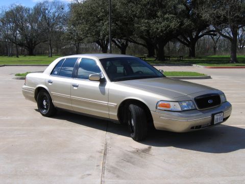 2000 Ford Crown Victoria - A gold 2000 Ford Crown Victoria is parked outdoors on a concrete surface.