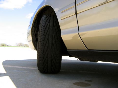 2000 Ford Crown Victoria - Side view of a tan 2000 Ford Crown Victoria, focusing on the door and tire.