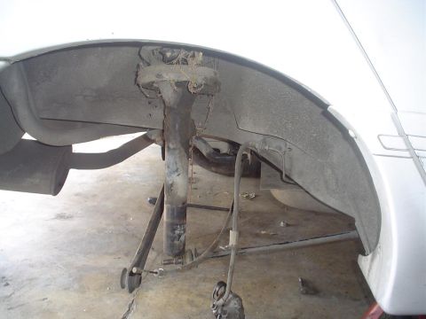 1993 Ford Taurus - Close-up view of the rear suspension strut and exhaust system of a white vehicle.