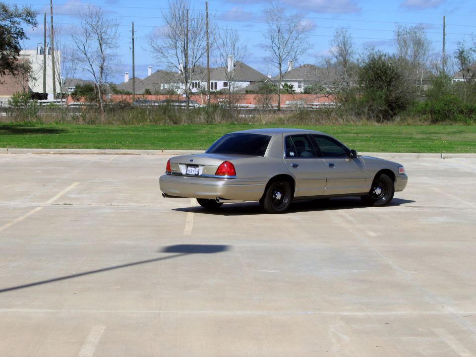 Tan 2000 Ford Crown Victoria sedan parked in a lot, rear passenger side view