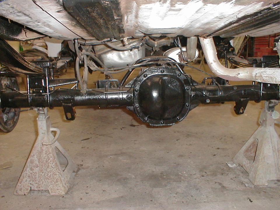 rear axle assembly on jack stands, showing leaf springs and exhaust pipe