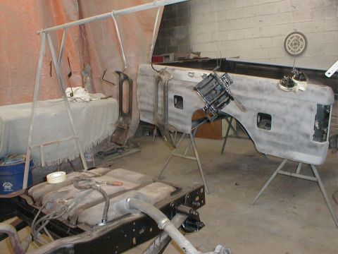 1991 Ford F-150 - A disassembled truck bed and fuel tank are in a workshop, undergoing preparation for custom paint work.