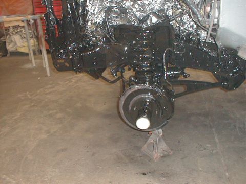 1991 Ford F-150 - Truck frame and suspension components are covered in black paint, supported by jack stands in a garage.
