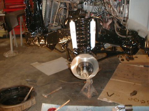1991 Ford F-150 - The front suspension and brake assembly of a vehicle is shown, with parts painted black and white shock absorbers.
