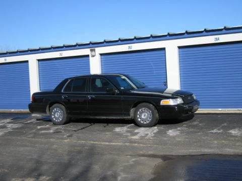1991 Ford LTD Crown Victoria - A black sedan is parked in front of a row of storage units on a sunny day.