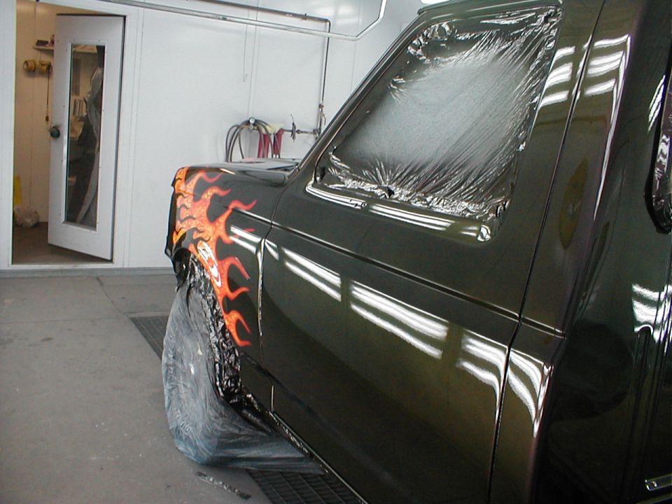 1991 Ford F-150 fender with flame paint, covered in plastic in a paint booth
