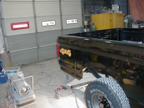 1991 Ford F-150 - Black Ford F-150 pickup truck rear quarter panel with 4x4 decal, parked in garage.