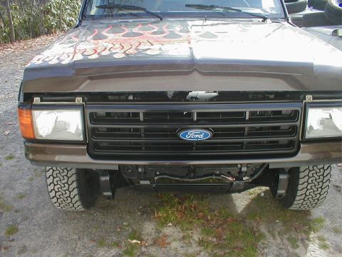 1991 Ford F-150 - The front grille and headlights of a brown Ford F-150 truck are visible, custom flame paint on the hood.