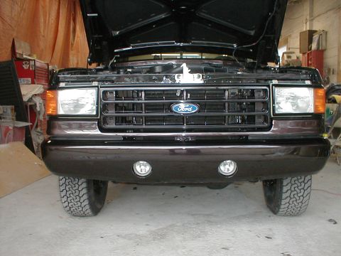 1991 Ford F-150 - Front view of a dark brown 1987 Ford F-150 with the hood open, showing the grille and fog lights.
