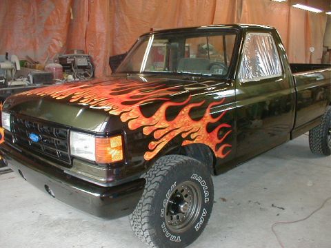 1991 Ford F-150 - Ford F-150 truck with custom flame paint job is shown from a three-quarter front angle in a workshop.