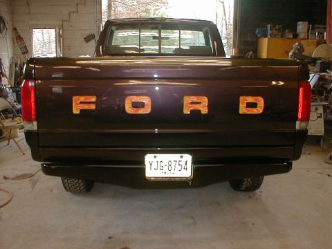 1991 Ford F-150 - Rear view of a dark brown 1991 Ford F-150 truck with custom flame-patterned tailgate lettering.