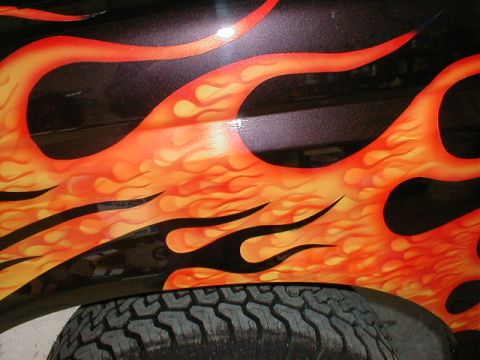 1991 Ford F-150 - Custom flame paint job on a vehicle's fender, with a tire visible below.