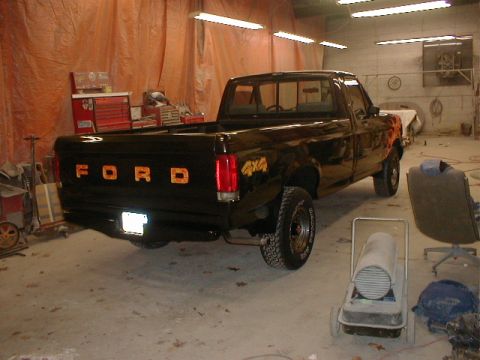 1991 Ford F-150 - Black 1991 Ford F-150 pickup truck with custom painted flames is parked in a garage.