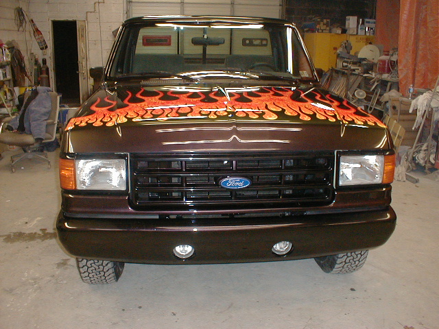 Dark brown 1991 Ford F-150 truck with orange and yellow flames painted on the hood, viewed from the front