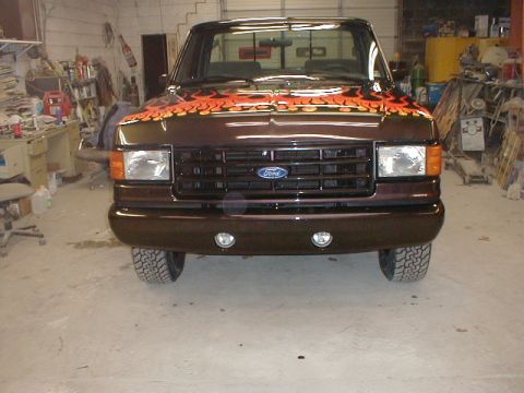 1991 Ford F-150 - Front view of a brown 1991 Ford F-150 truck with custom flame graphics on the hood, parked indoors.