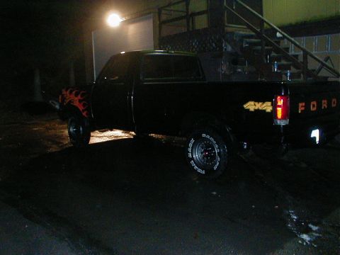 1991 Ford F-150 - A black Ford F-150 pickup truck is parked outside at night, illuminated by a bright overhead light.