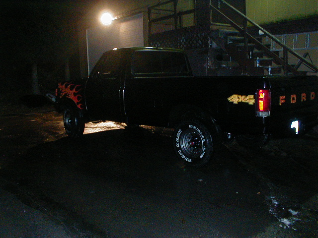Black Ford F-150 pickup truck with flame decals on the front fender and 4x4 badging on the rear fender