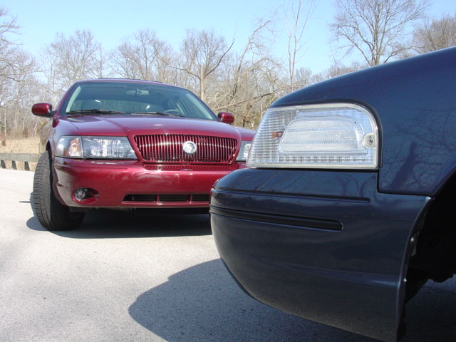 Maroon sedan front and dark blue sedan corner facing off in a parking lot