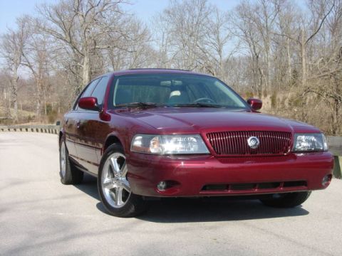 1998 Ford Crown Victoria - Three-quarter front view of a dark red Mercury Marauder sedan with its vertical-slat grille, Mercury emblem, clear-lens headlights, and chr…