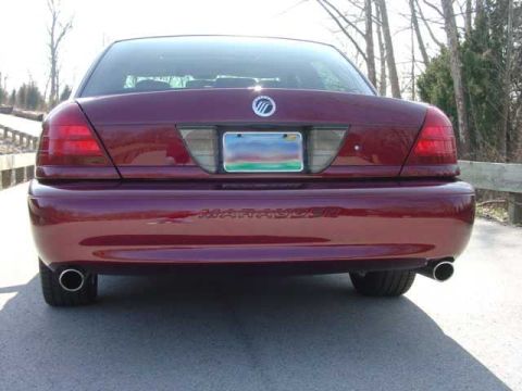 1998 Ford Crown Victoria - Rear view of a dark red/maroon Mercury sedan with dual chrome exhaust tips, a center-mounted license plate flanked by tail lights, and a Me…