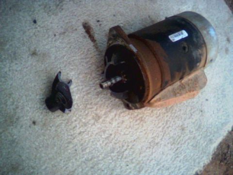 1987 Ford Bronco - A starter motor and its broken solenoid are shown on a carpeted surface. The Supermotors.net logo is visible in the lower right corner.