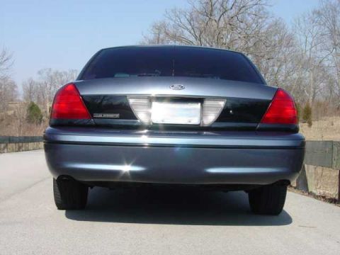 1998 Ford Crown Victoria - Straight-on rear view of a gray-blue Ford Crown Victoria with a black decklid trim panel, a small Police Interceptor badge, and dual exhaus…