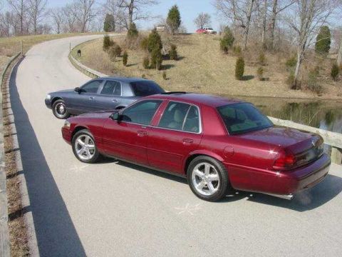 1998 Ford Crown Victoria - Elevated view looking down on a burgundy Mercury full-size sedan with chrome five-spoke wheels, sunroof, and dual exhaust tips, parked on a…