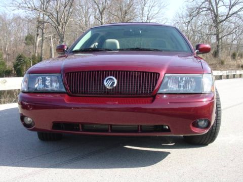1998 Ford Crown Victoria - Front view of a maroon full-size Mercury sedan with a blacked-out waterfall grille, chrome surround, Mercury emblem, and projector-style he…