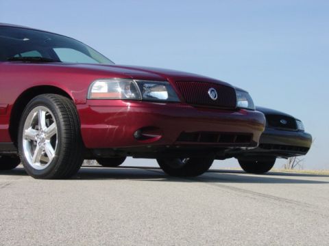 1998 Ford Crown Victoria - Low front-end shot of a dark red Mercury Marauder beside a black Ford sedan on pavement.
