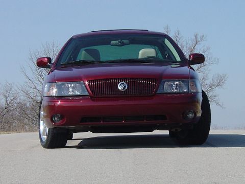 1998 Ford Crown Victoria - Head-on low front view of a dark toreador red Mercury Marauder sedan parked on pavement, showing its vertical-slat grille with Mercury embl…