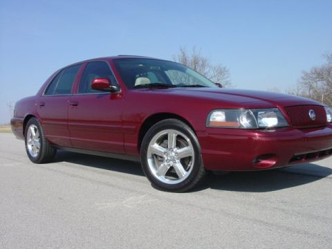 1998 Ford Crown Victoria - Low front three-quarter view of a dark red Mercury Marauder sedan with its blacked-out headlamp bezels, Mercury waterfall grille, bumper fo…