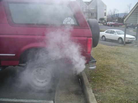 1994 Ford Bronco - A red SUV, possibly a Ford Bronco, emits a large cloud of smoke from its exhaust pipe.