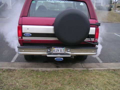 1994 Ford Bronco - A red 1994 Ford Bronco is seen from the rear, emitting smoke from its exhaust pipe.