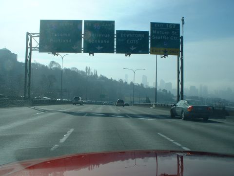 1999 Ford Crown Victoria - Driving on a highway with multiple lanes and traffic, approaching a city.