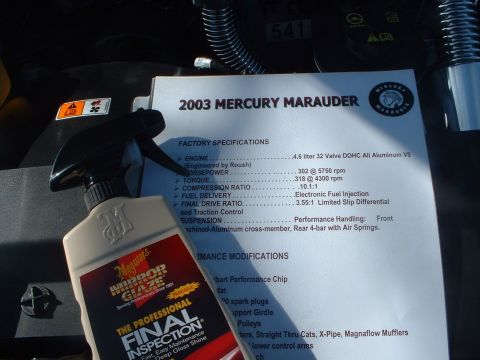 1999 Ford Crown Victoria - A document detailing the 2003 Mercury Marauder's specifications sits next to a bottle of car detailing spray.