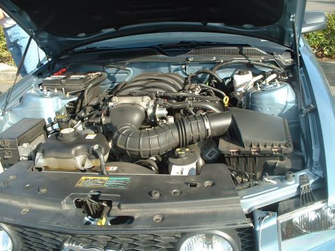 1999 Ford Crown Victoria - The engine bay of a light blue vehicle is shown with the hood open, revealing the engine and various components.