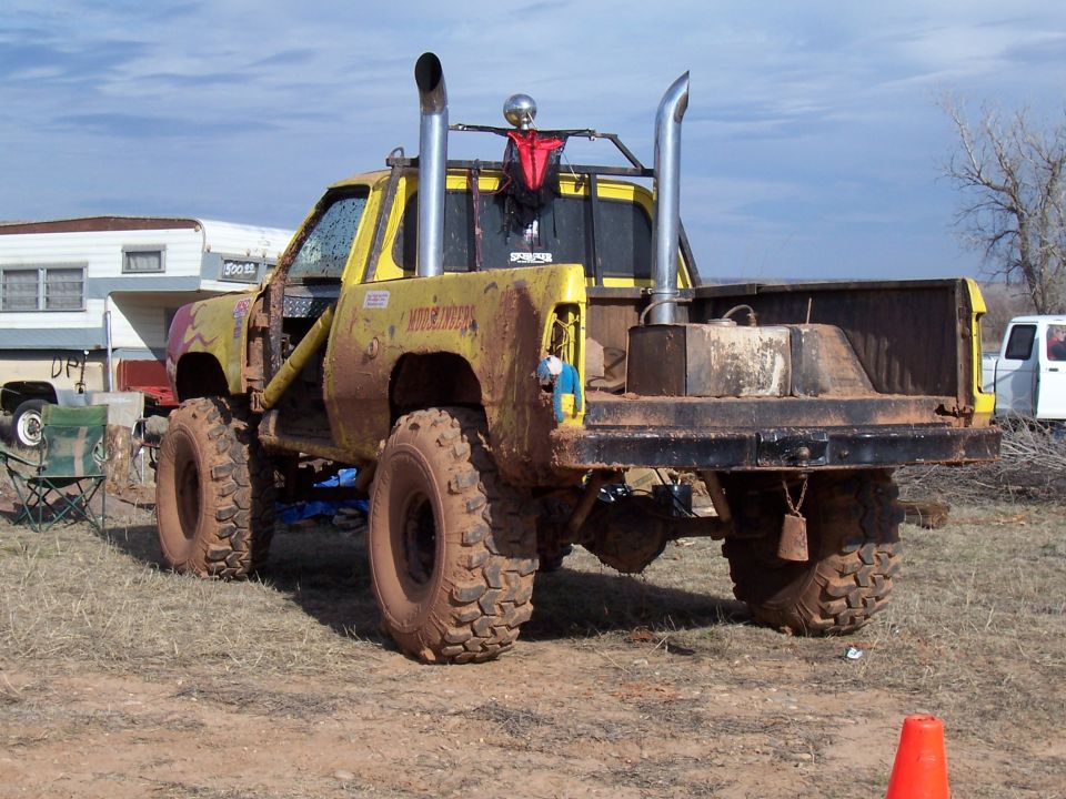 Muddy yellow lifted mud truck with twin chrome stacks and oversized tires
