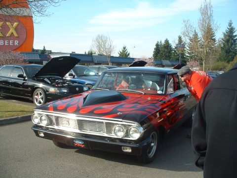 1999 Ford Crown Victoria - A custom car with flame graphics is displayed outdoors, with another vehicle's engine visible.
