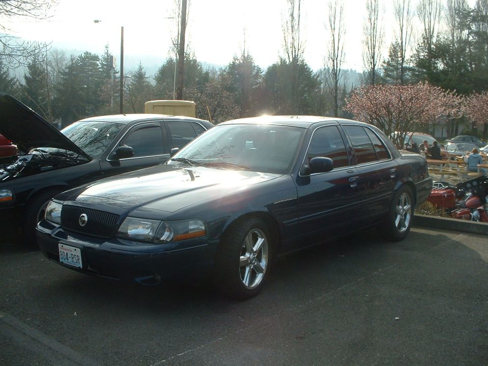 Dark sedan with chrome wheels, hood open on car next to it. License plate is 804-PCR