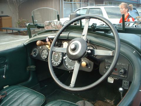 1999 Ford Crown Victoria - The dashboard of a classic car features numerous analog gauges and a prominent steering wheel, with a woman visible outside.