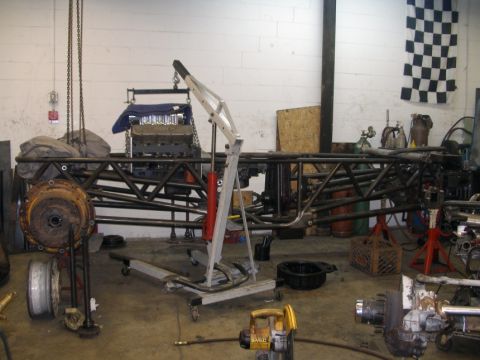 1994 Ford Bronco - A disassembled vehicle chassis and engine are in a workshop, awaiting assembly or repair.