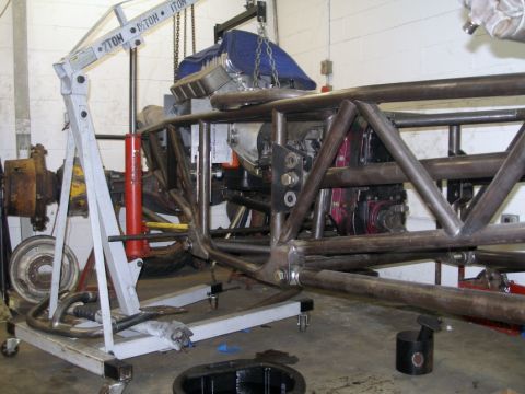 1994 Ford Bronco - A custom tube chassis is shown with an engine and transmission being worked on in a garage setting.