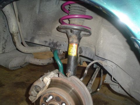 1993 Ford Taurus - Close-up of a vehicle's suspension system, showing a strut, coil spring, and brake components.
