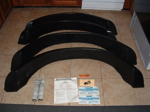 1993 Ford Bronco - A set of four black fender flares, along with sealant and instructions, are laid out on a tiled floor.