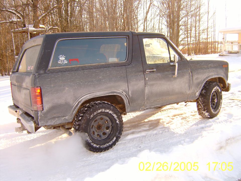 Gray Ford Bronco driving in snow, kicking up dust from rear tire
