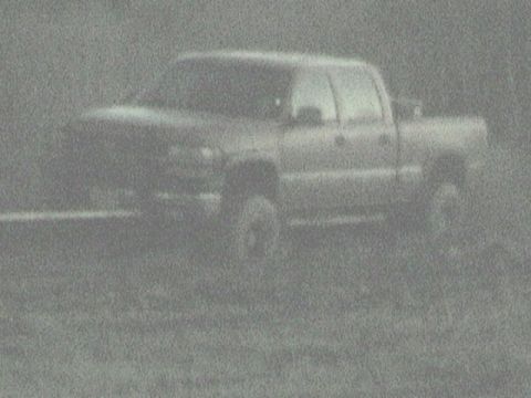 1989 Ford Bronco - A grainy photo shows a pickup truck from the front-three-quarter angle, parked outdoors.