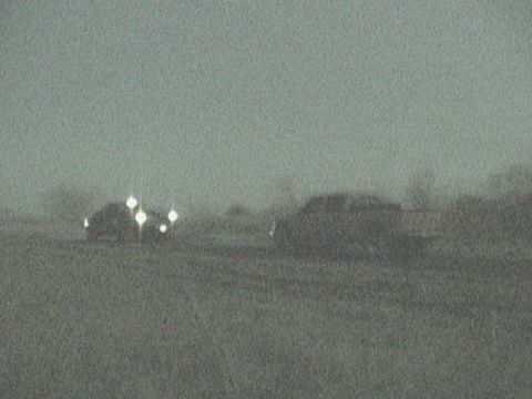 1989 Ford Bronco - Two SUVs are visible in a grainy, low-light scene, with one vehicle displaying several bright headlights.